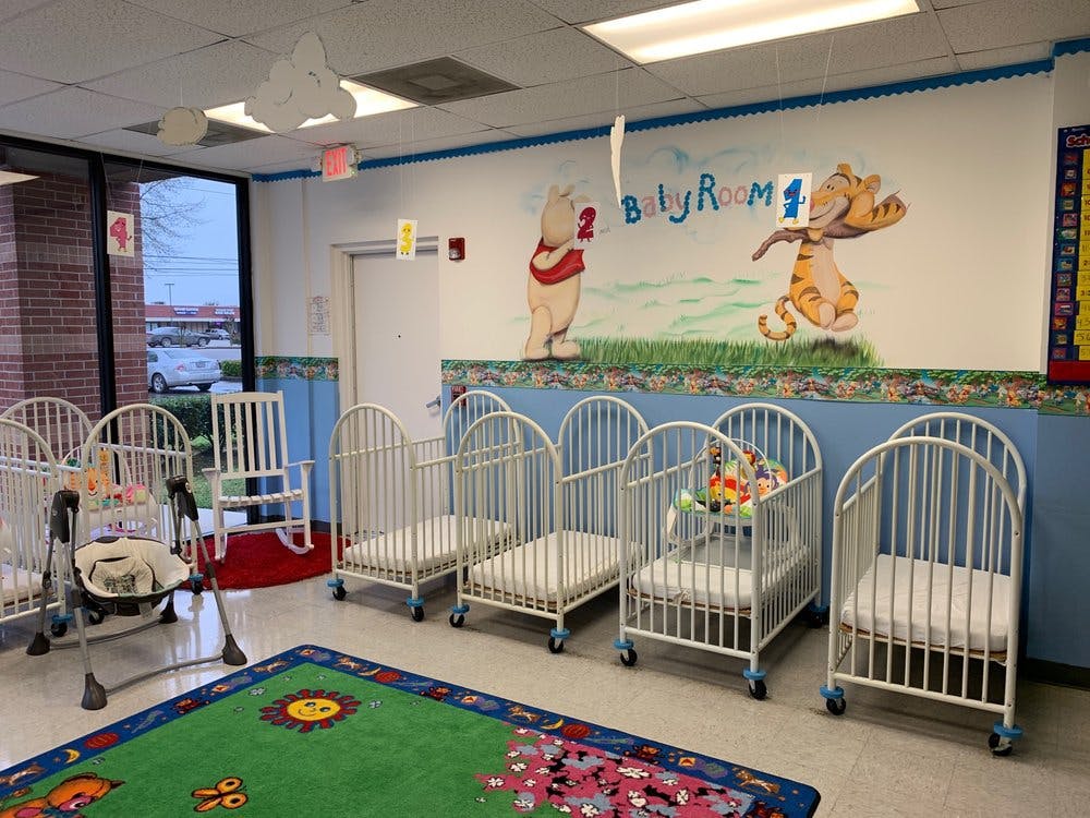 Nursery room with multiple white cribs and a colorful rug