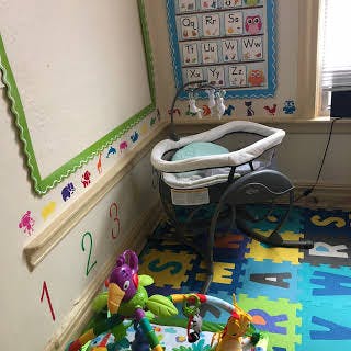 Baby bassinet and play mat in a room with alphabet and number decorations