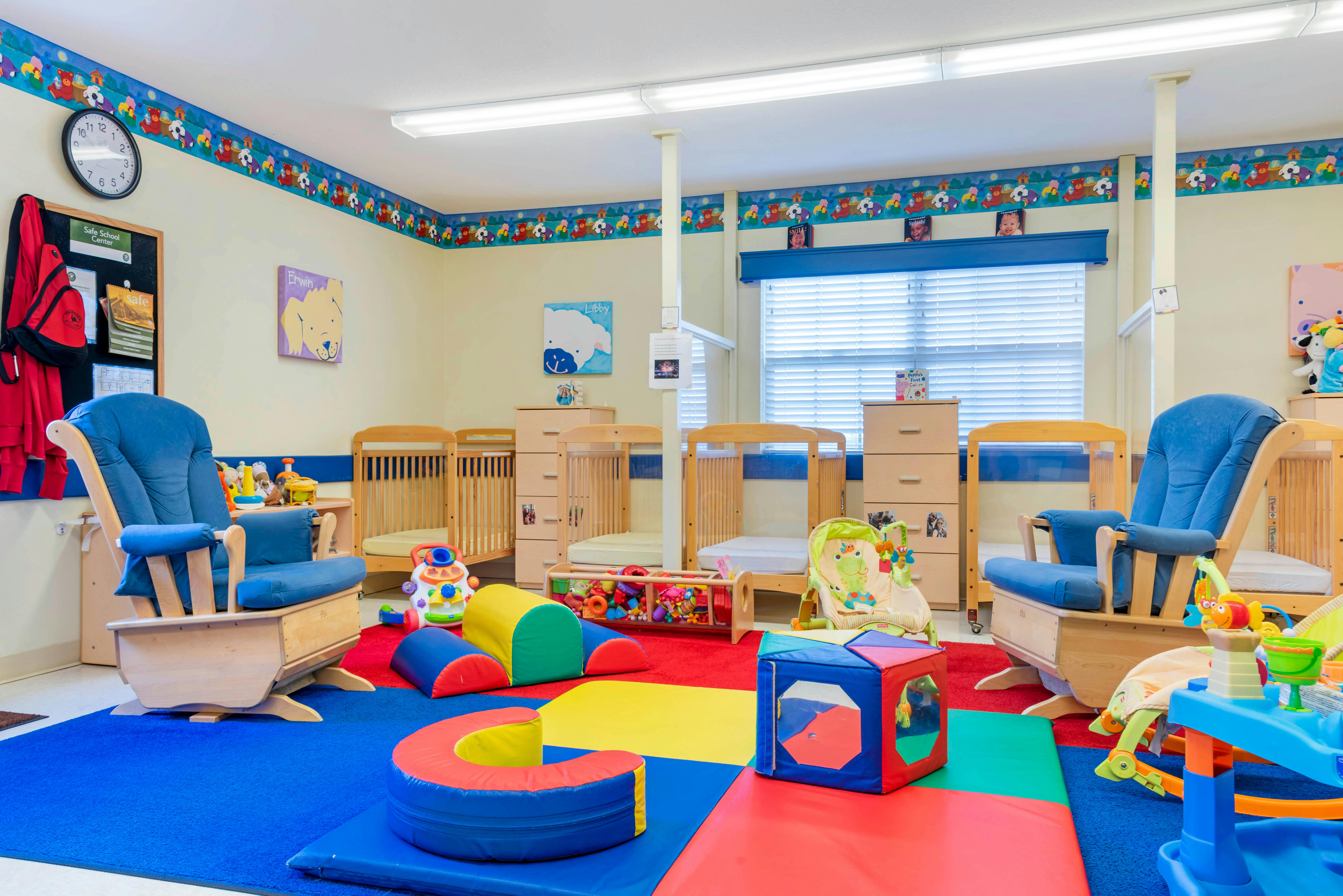 A colorful playroom with cribs, chairs, and soft play equipment