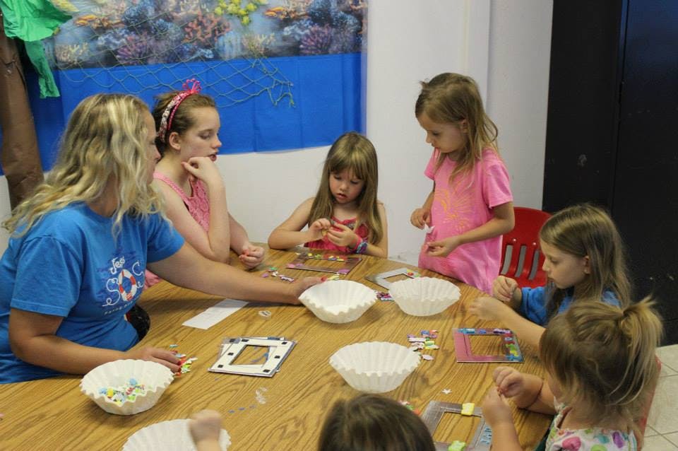 Adult and children sitting at a table doing crafts