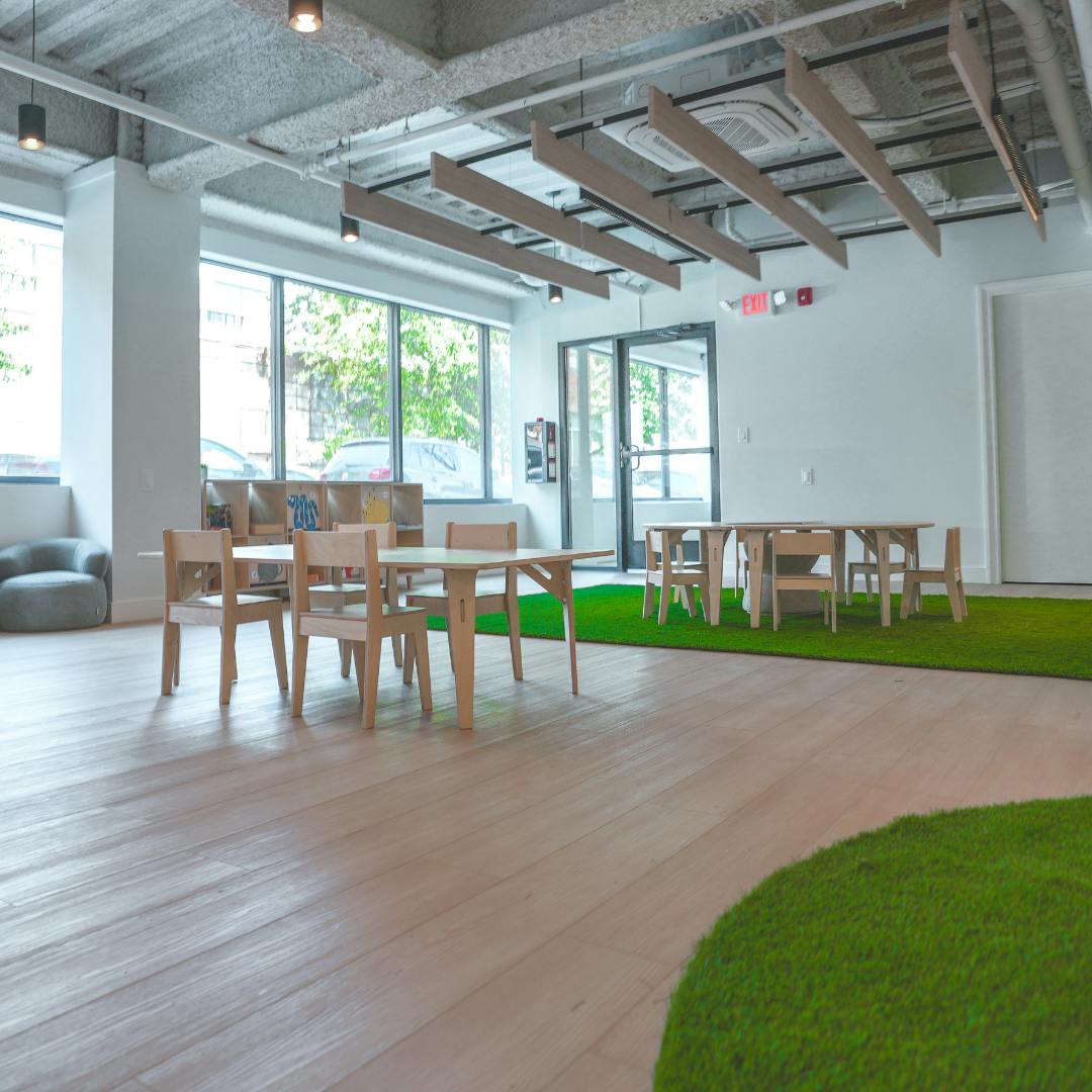 Room with small tables and chairs on wood floor and green turf