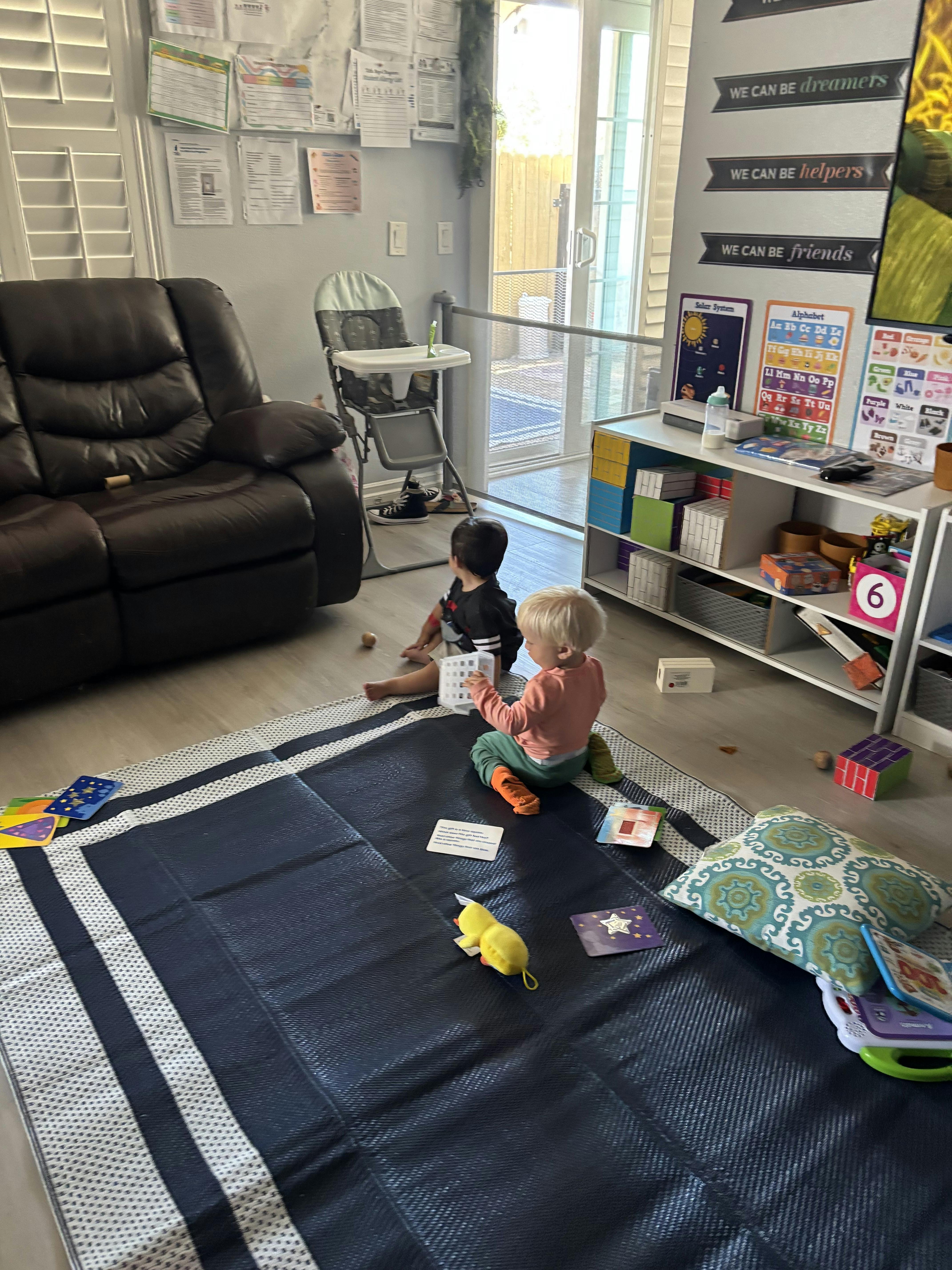 Two children sitting on a mat playing with toys