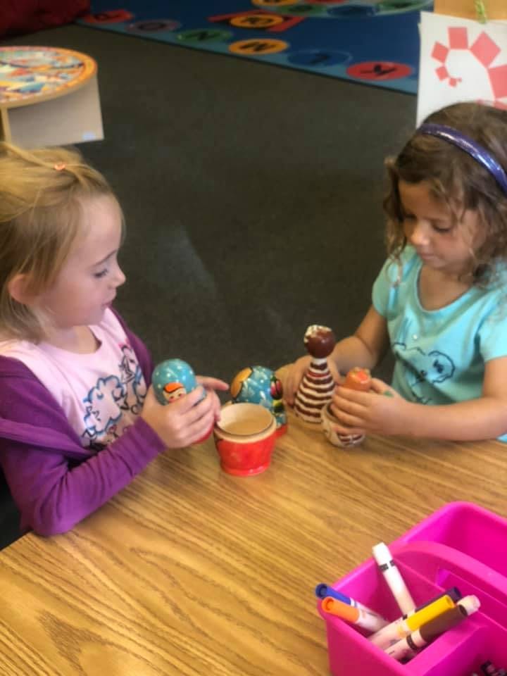 Two children playing with nesting dolls at a table