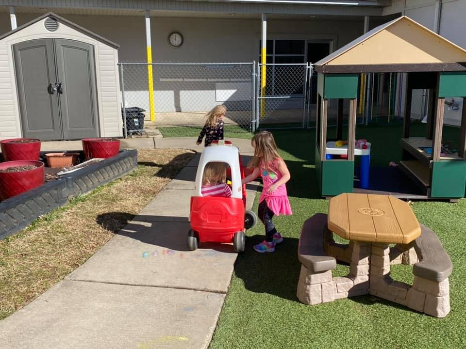 Two children playing with a toy car on a playground