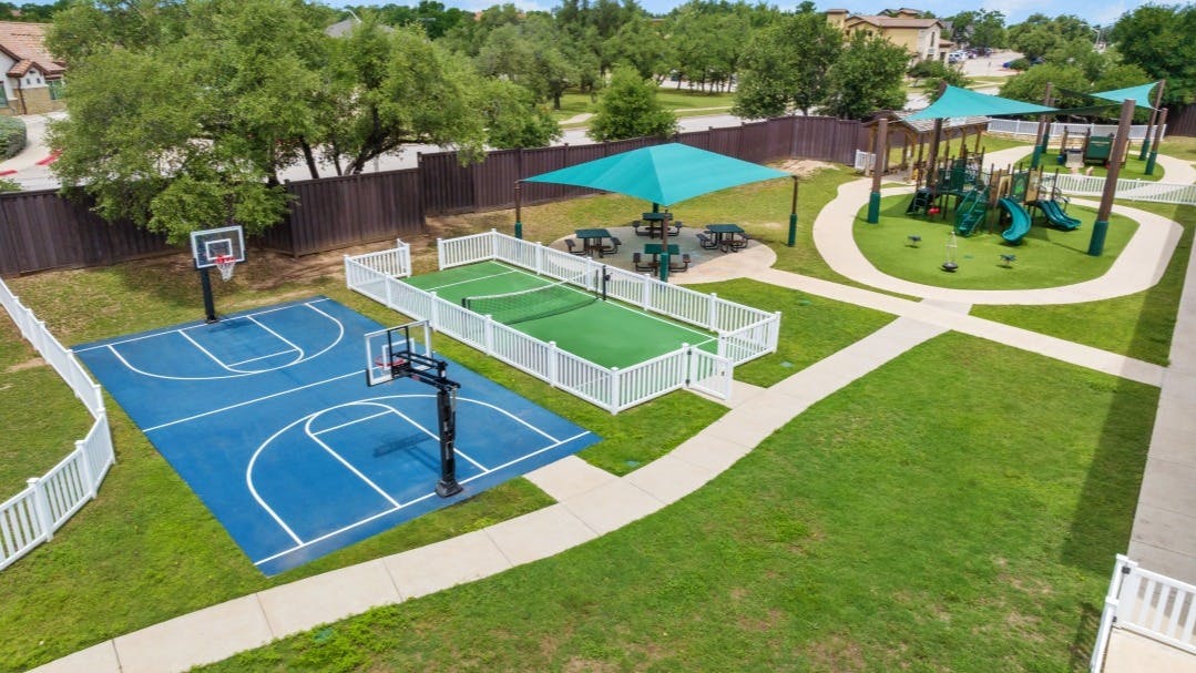 An outdoor recreational area with a basketball court, tennis court, and playground