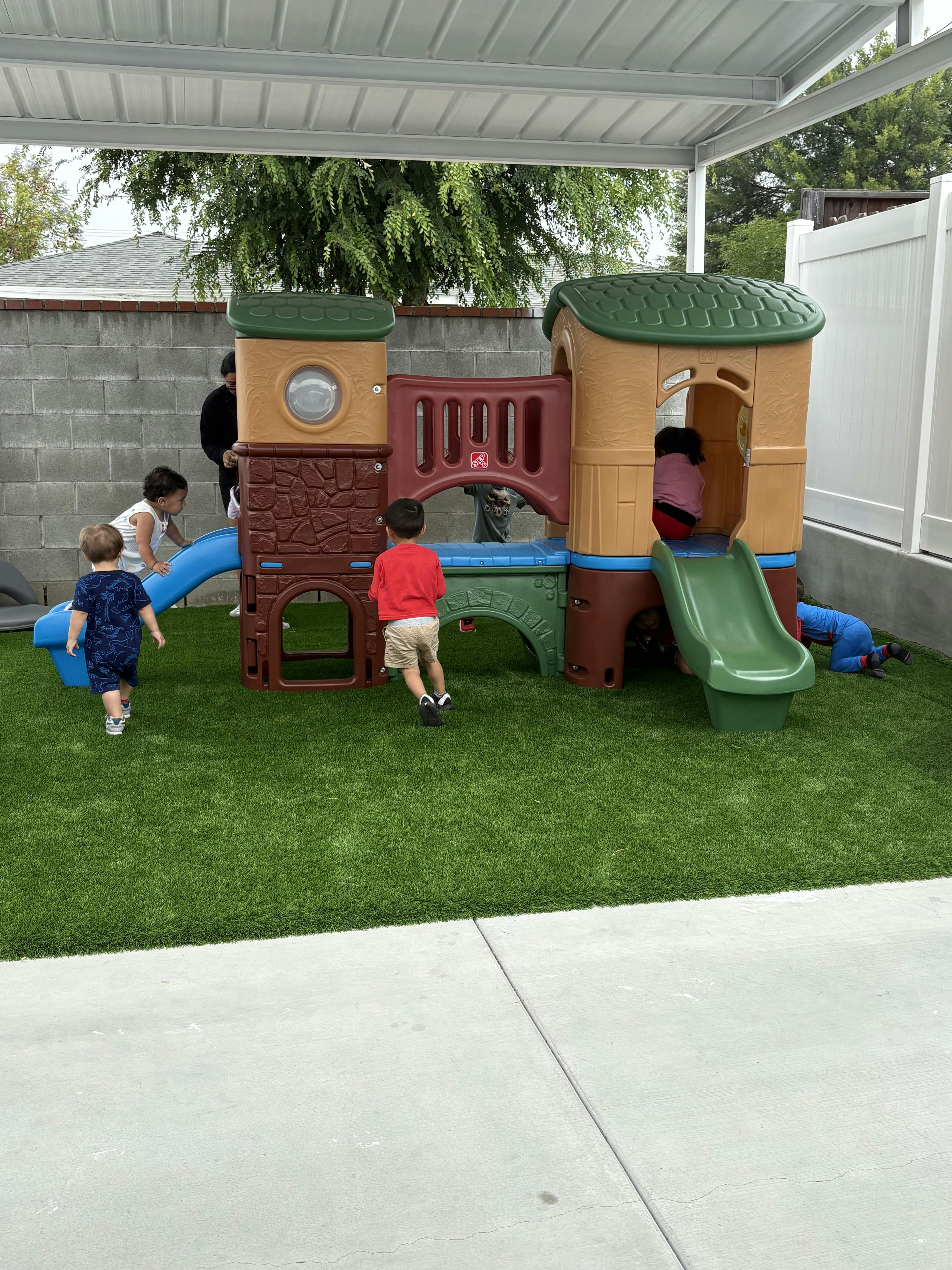 Group of children playing on a plastic climbing set on artificial grass