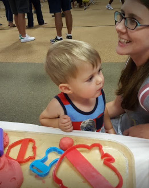 Child and person playing with playdough and cookie cutters