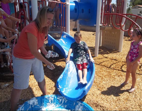 Person and child playing on a blue slide at a playground