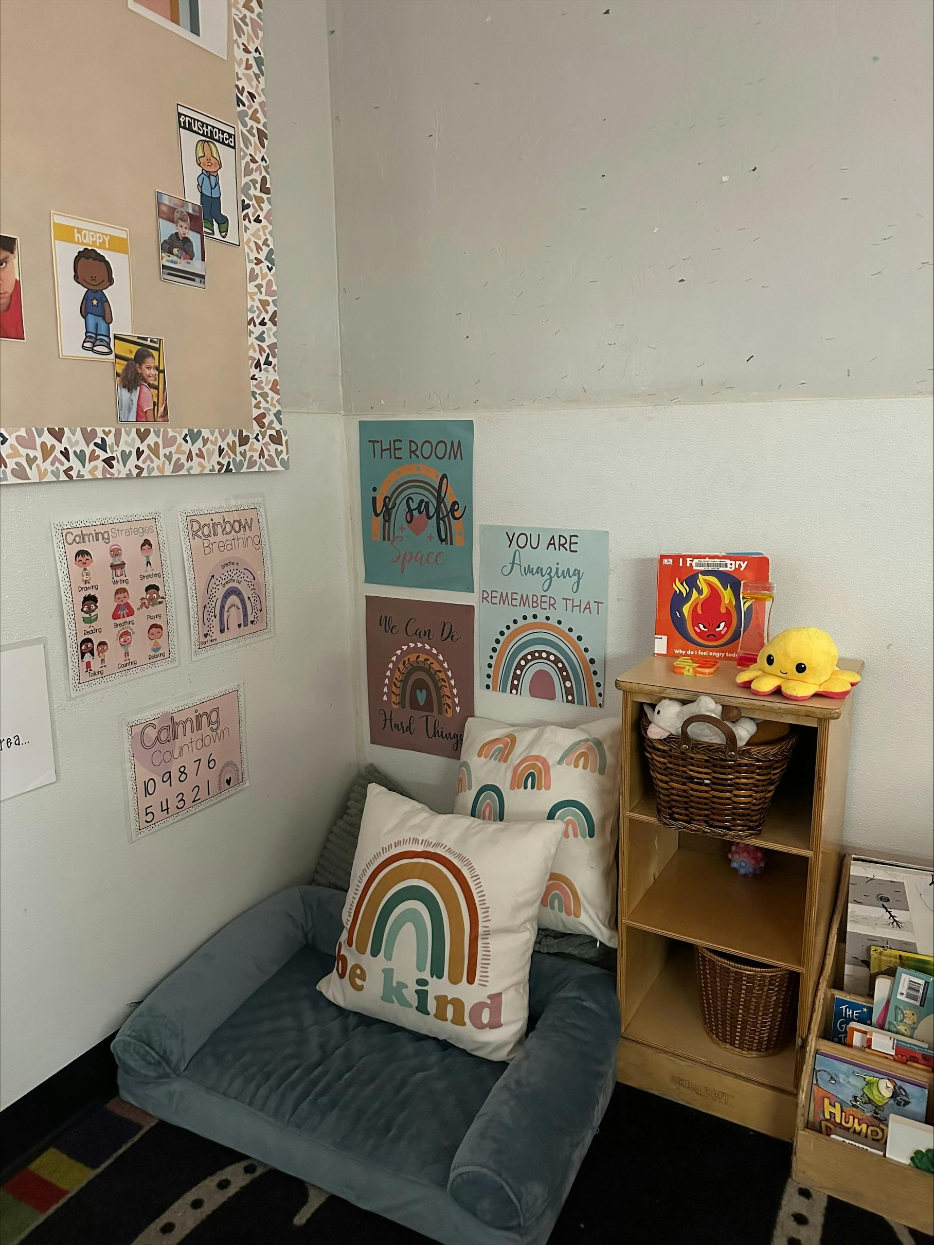 Corner of a classroom with a small couch, rainbow pillows, and posters