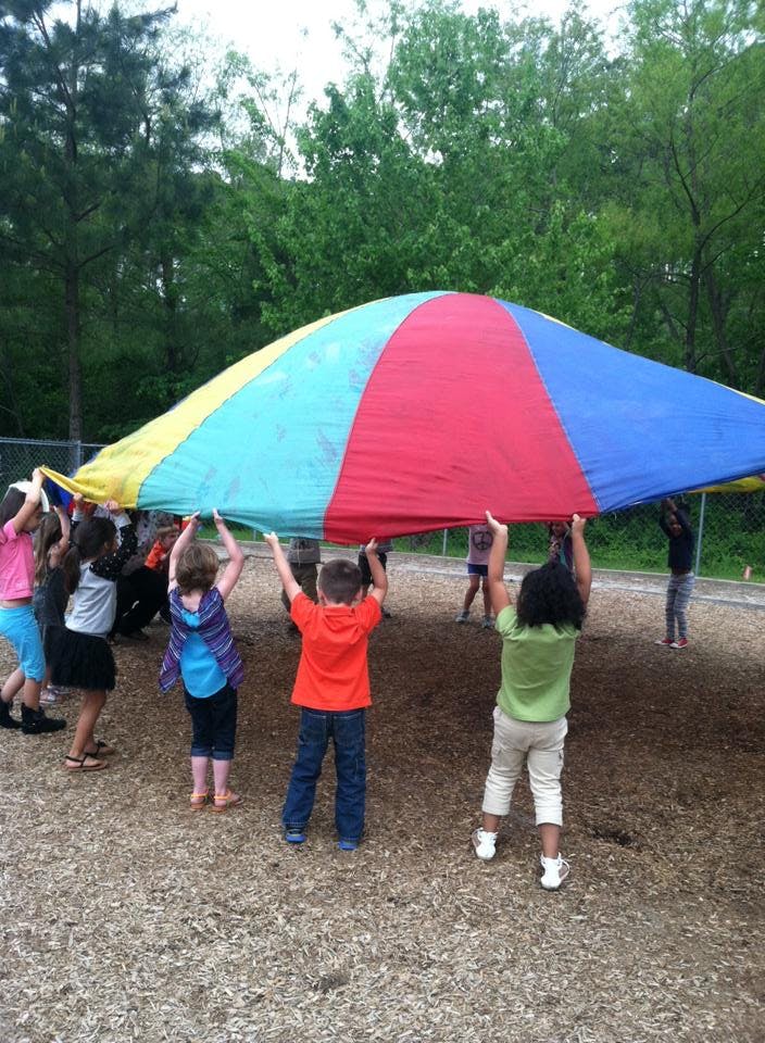 Children holding up a colorful parachute outdoors