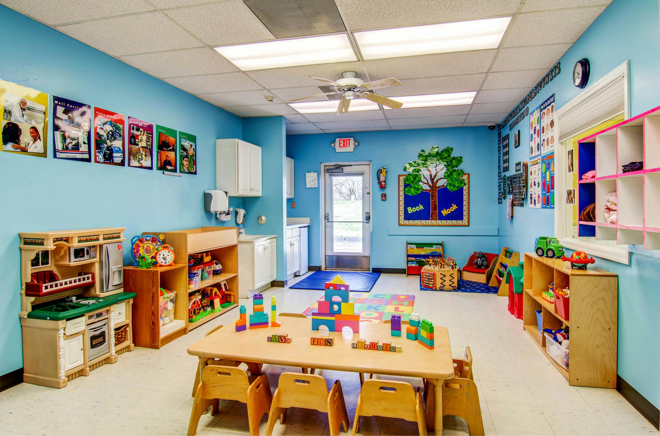 Classroom with blue walls, small tables, chairs, and toys