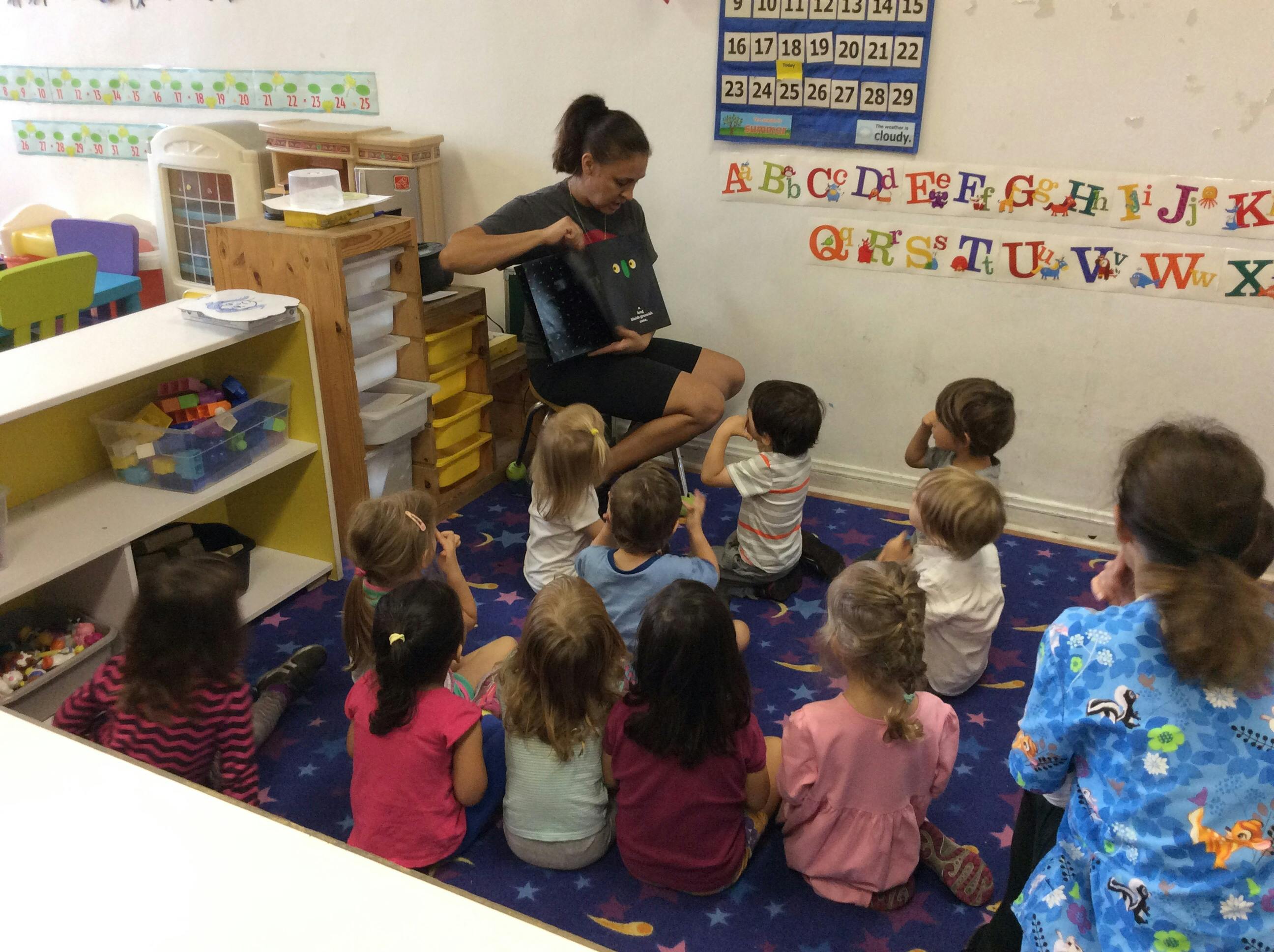Person reading to a group of children in a classroom