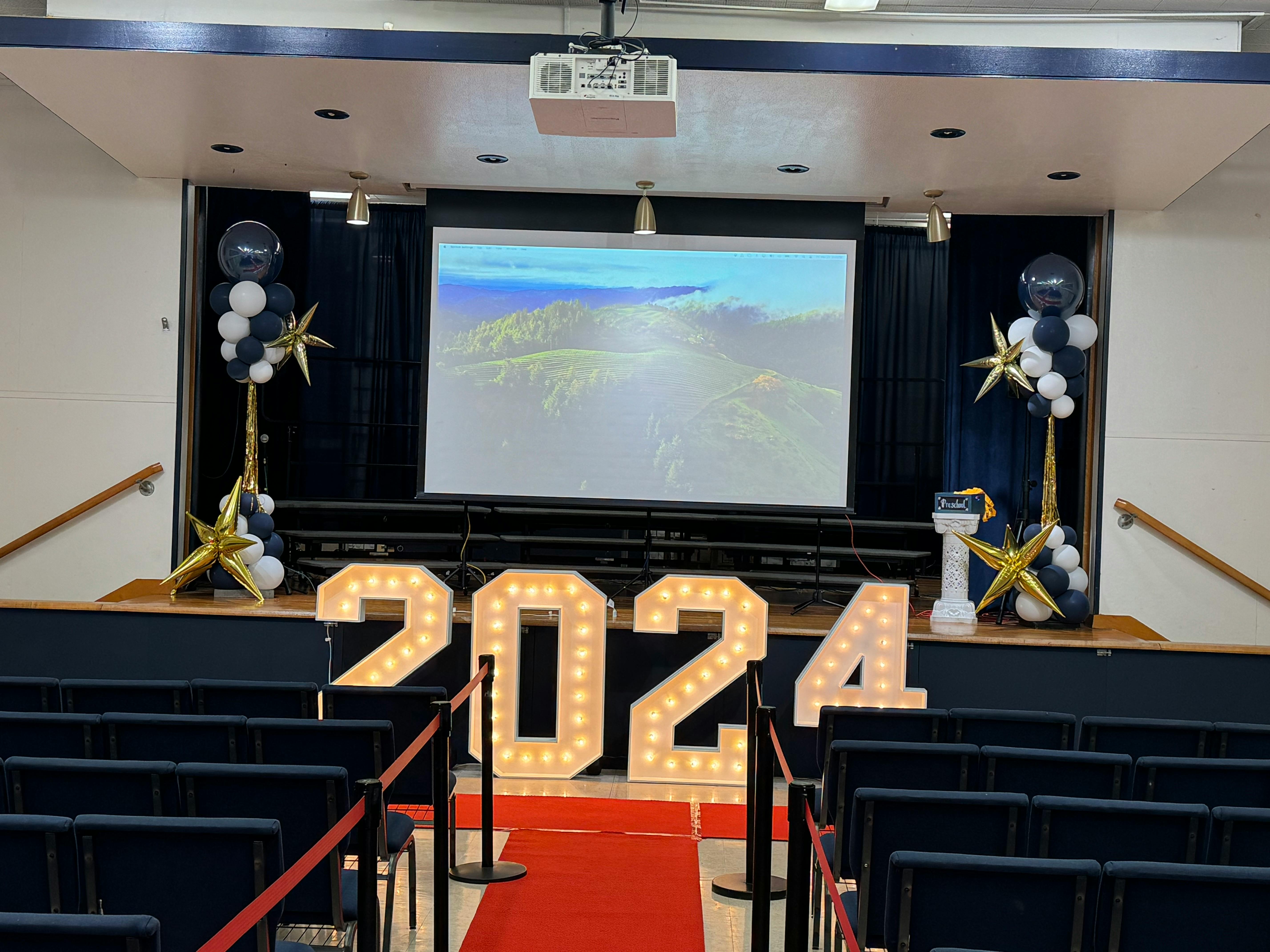 Stage with large illuminated numbers "2024" and balloon decorations