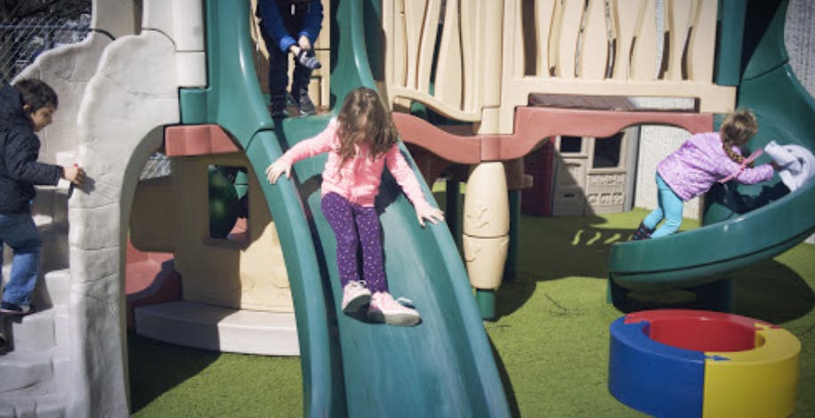 Children playing on a playground slide and climbing structure