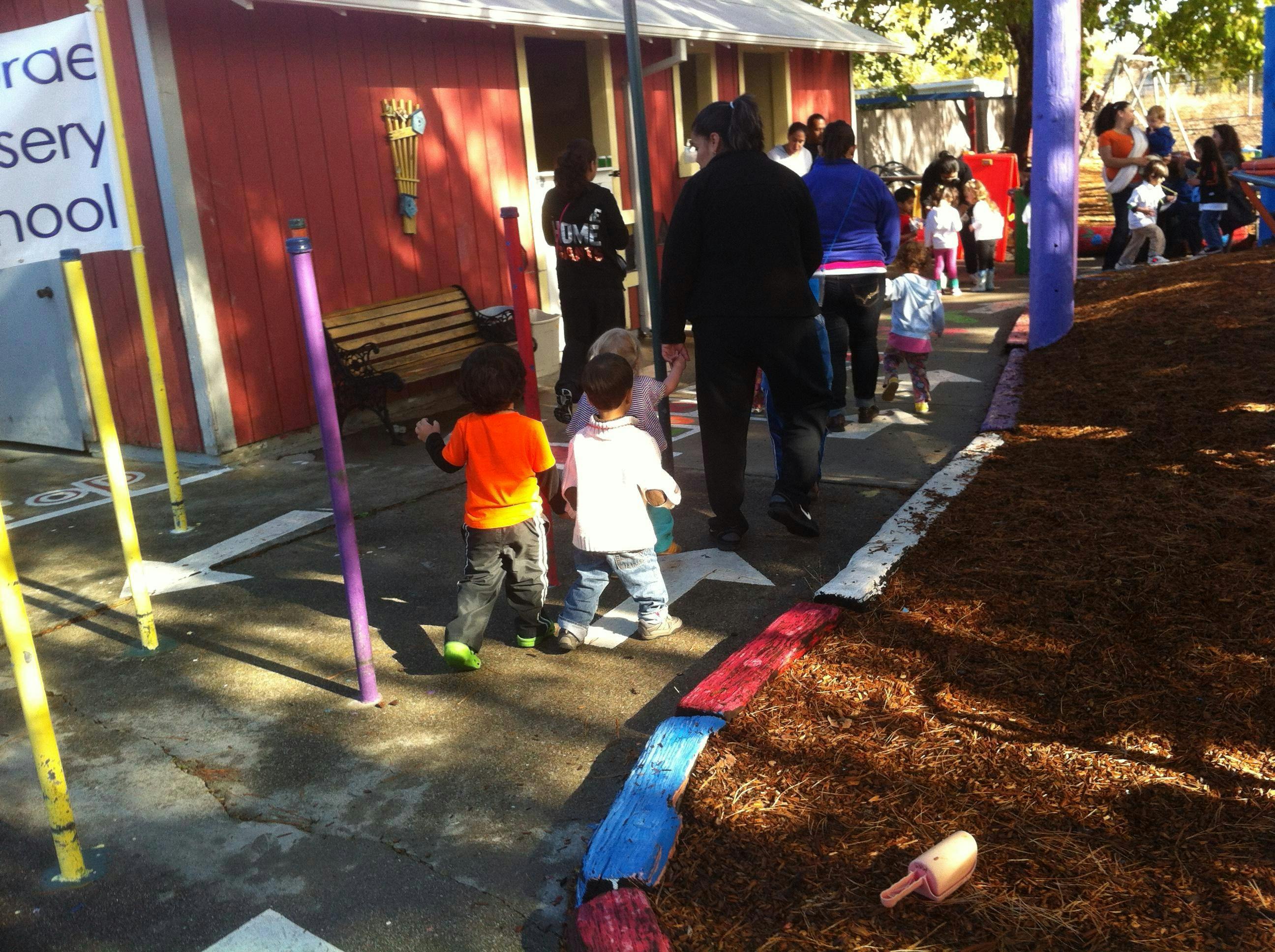 Children and adults walking on a paved path next to a building