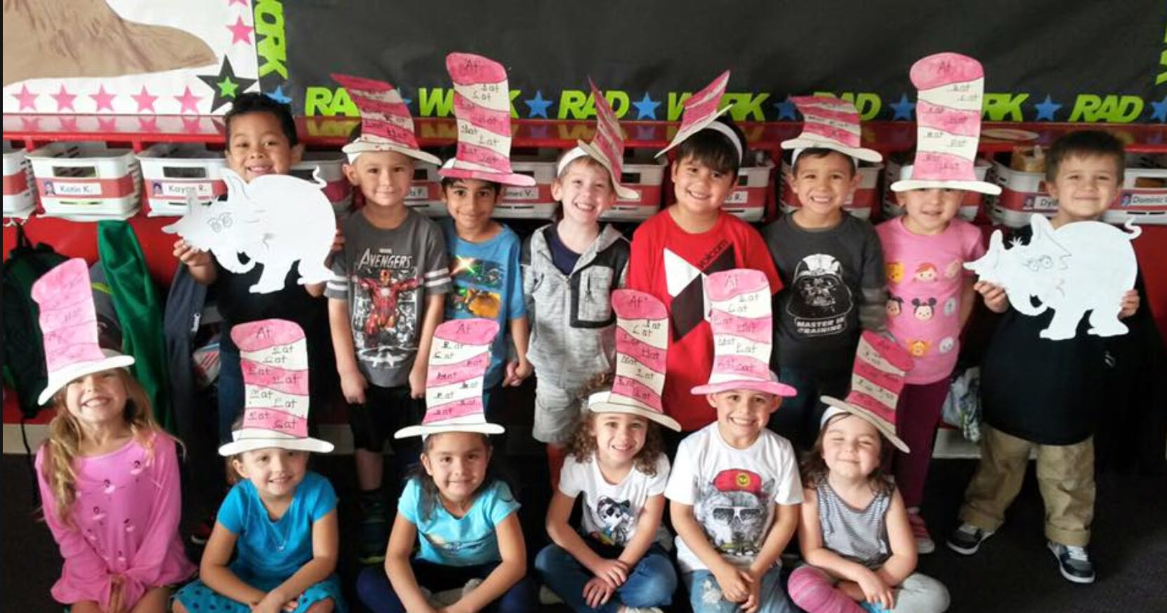 Group of children wearing striped hats, some holding animal cutouts