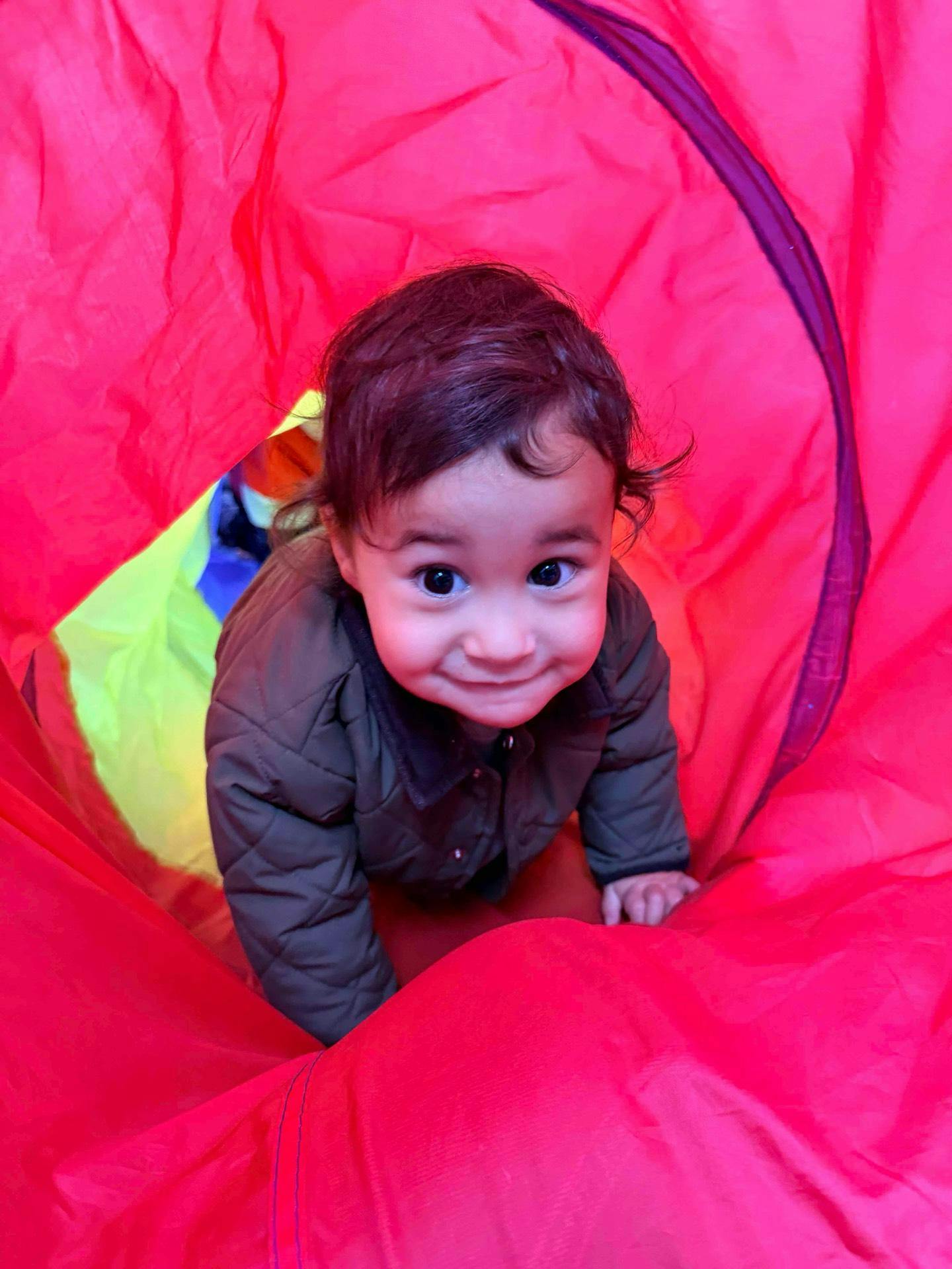 Child crawling through a brightly colored play tunnel