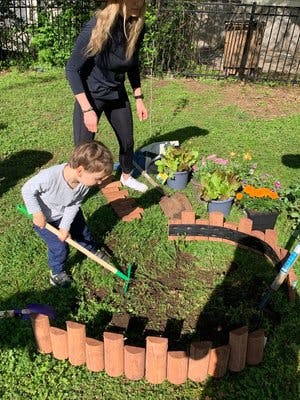 Adult and child gardening, child raking soil