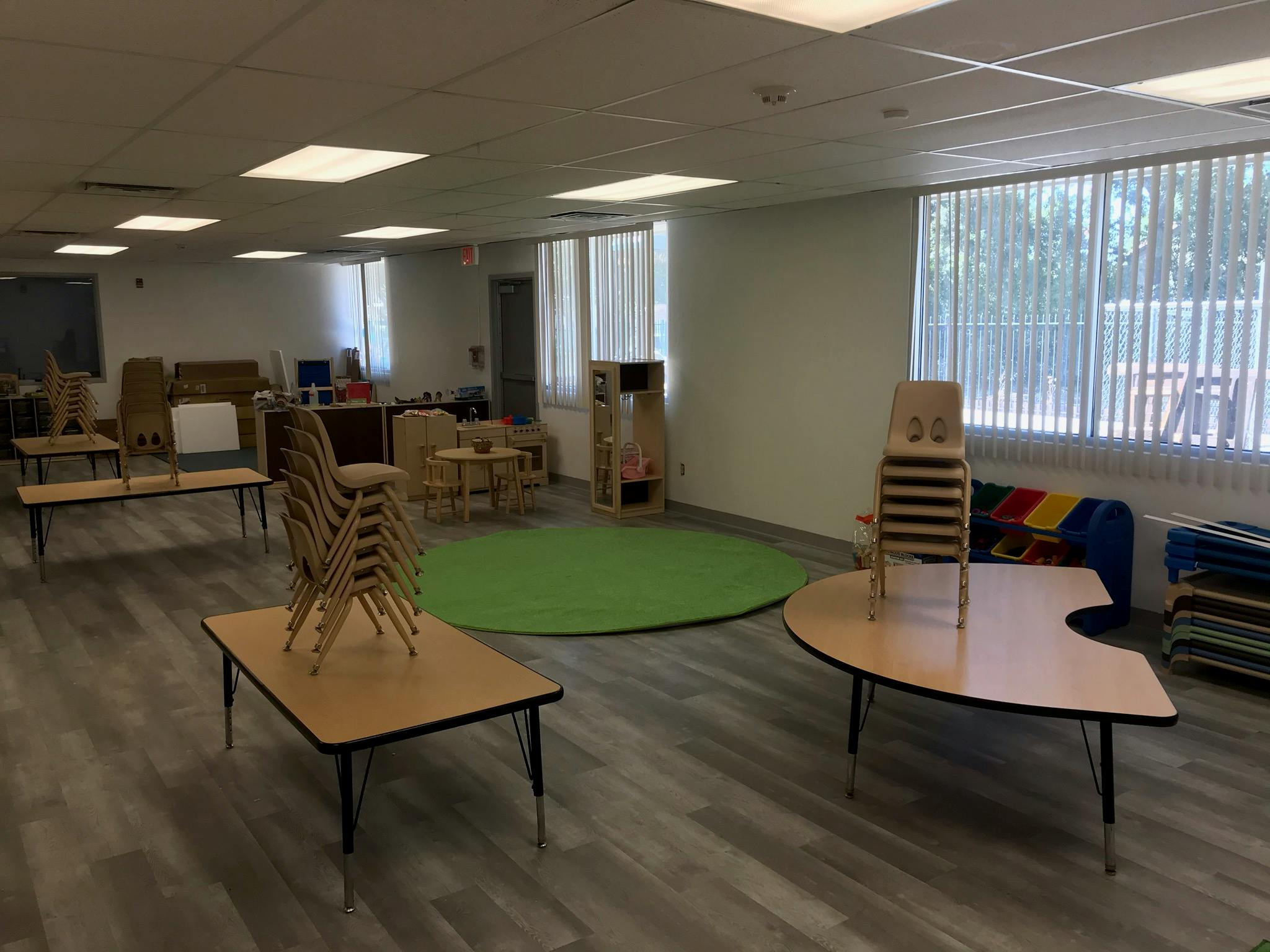 Empty classroom with small tables and stacked chairs