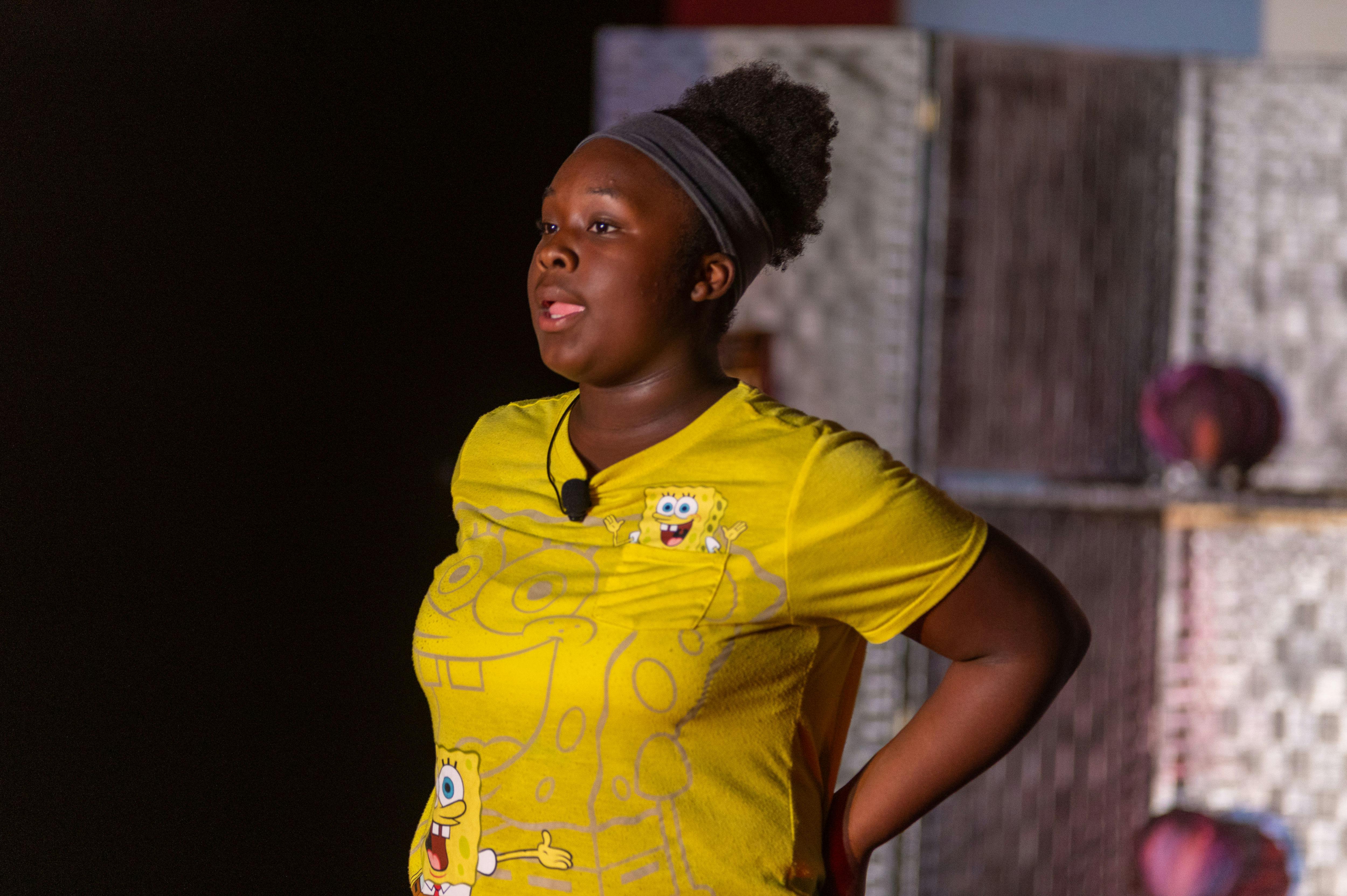 Teen in yellow shirt with microphone speaking
