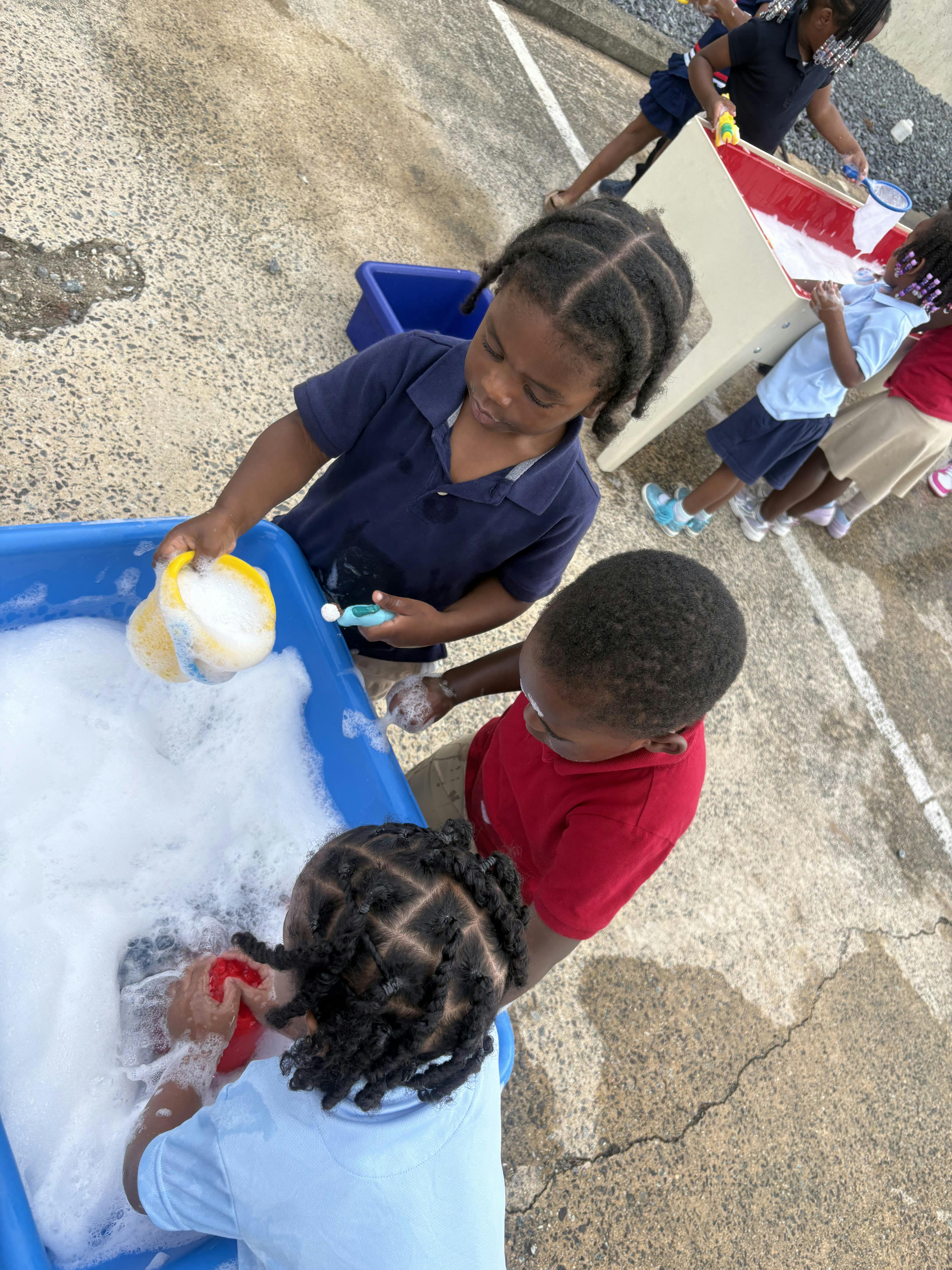 Children playing with soap bubbles in a water table outdoors