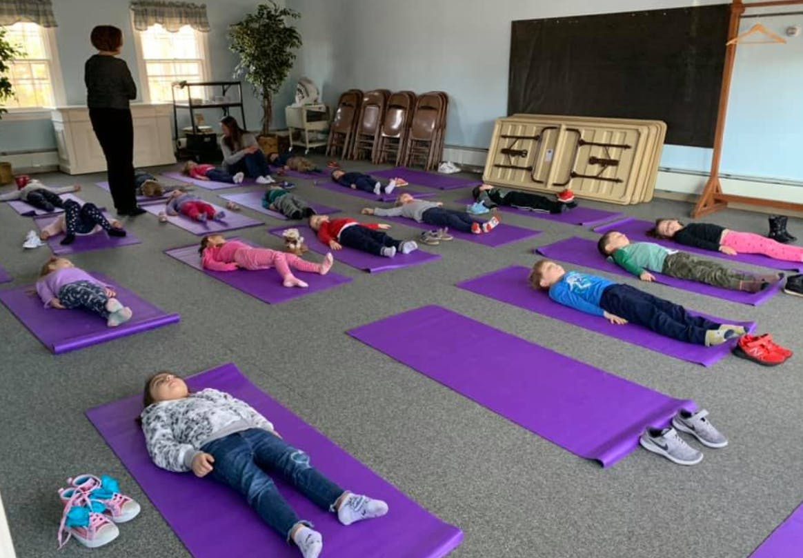 Adult and children lying on yoga mats in a room