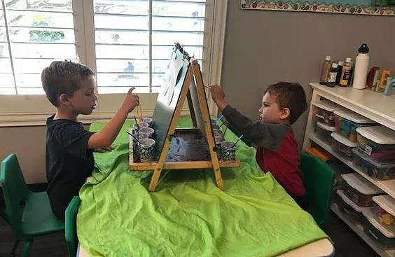 Two children painting at an easel on a table