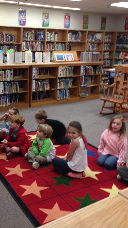 Children sitting on a star-patterned rug in a library