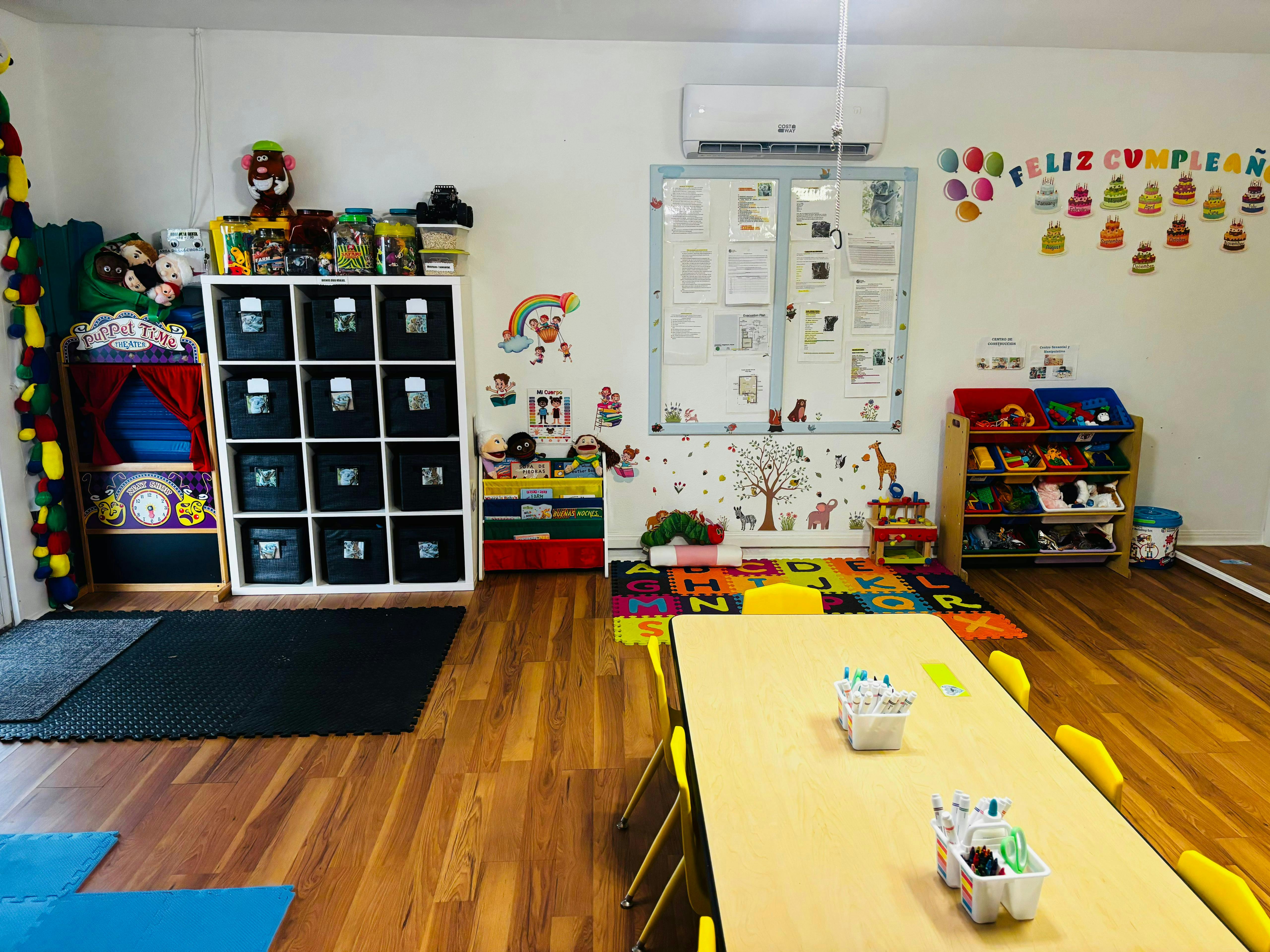 A classroom with tables, chairs, and storage units for toys and supplies