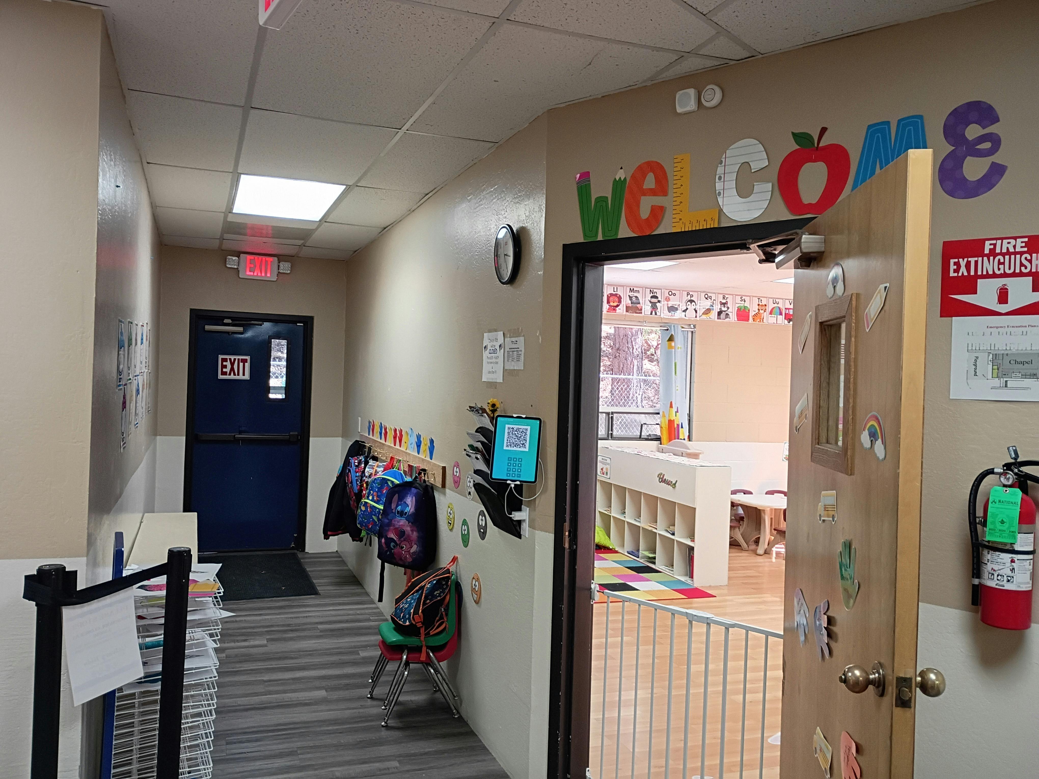 Hallway with open door to a classroom, welcome sign above door
