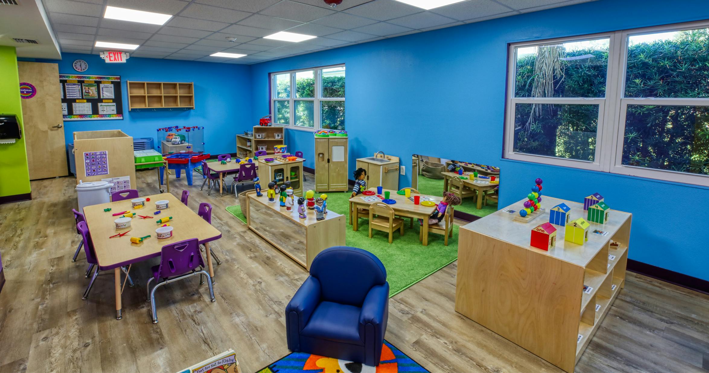 An empty early childhood classroom with multiple tables and chairs