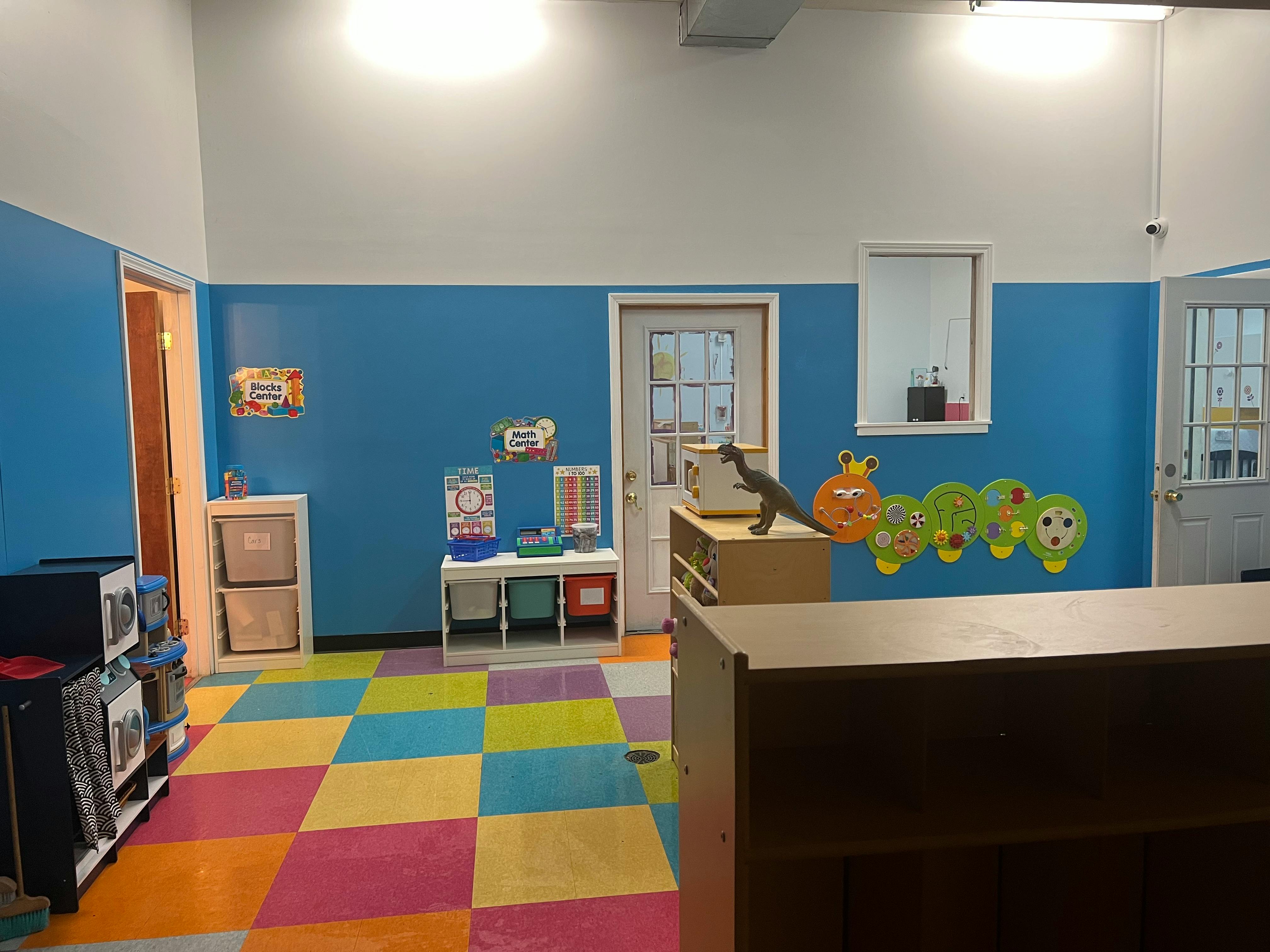 Classroom with blue walls, colorful checkered floor, and child-friendly decor