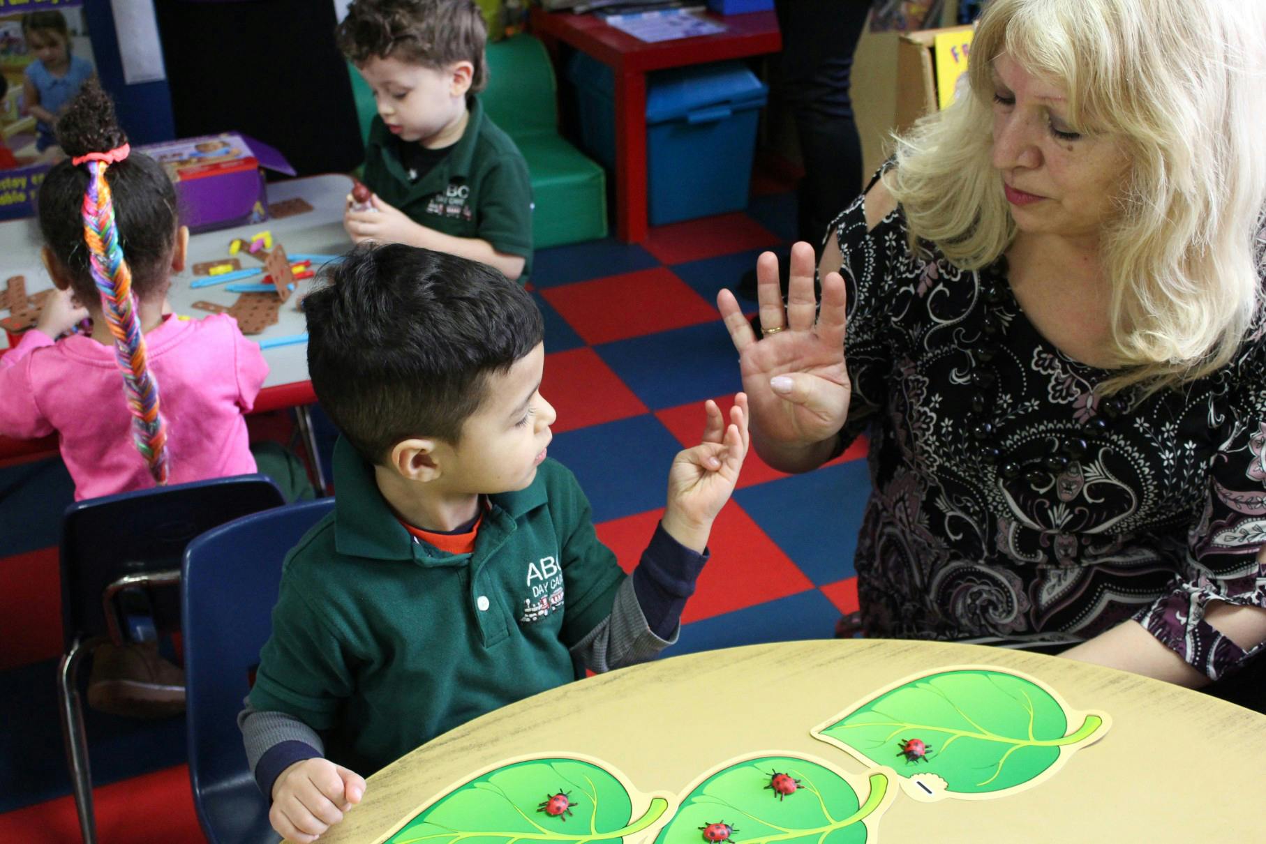 Adult and child interacting at a table in a classroom