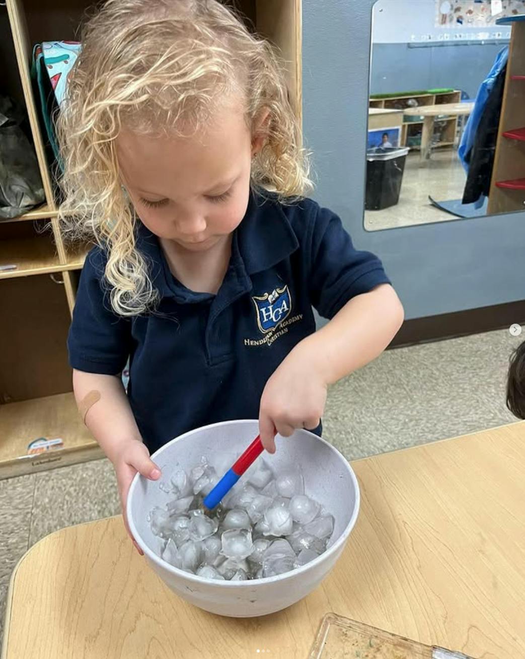 Child stirring a bowl of ice cubes with a small tool