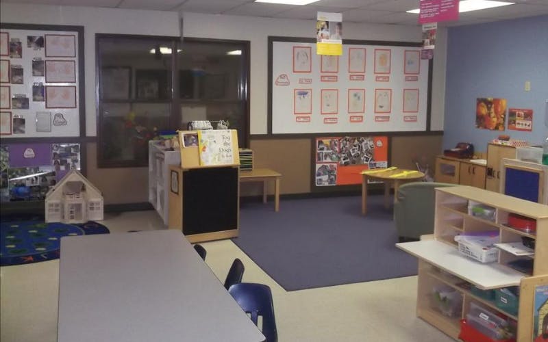 Classroom with children's artwork displayed, tables, chairs, and play furniture