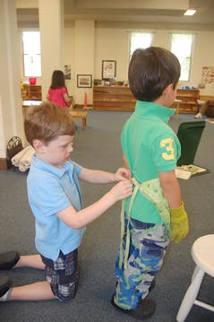 Child tying an apron on another child