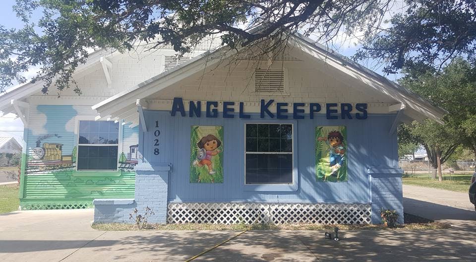 Building with "ANGEL KEEPERS" sign and child murals