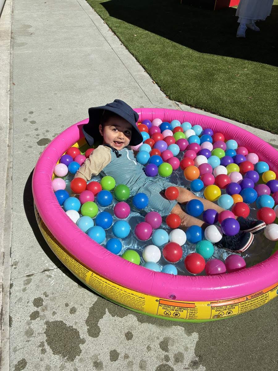 Child sitting in an inflatable pool filled with plastic balls