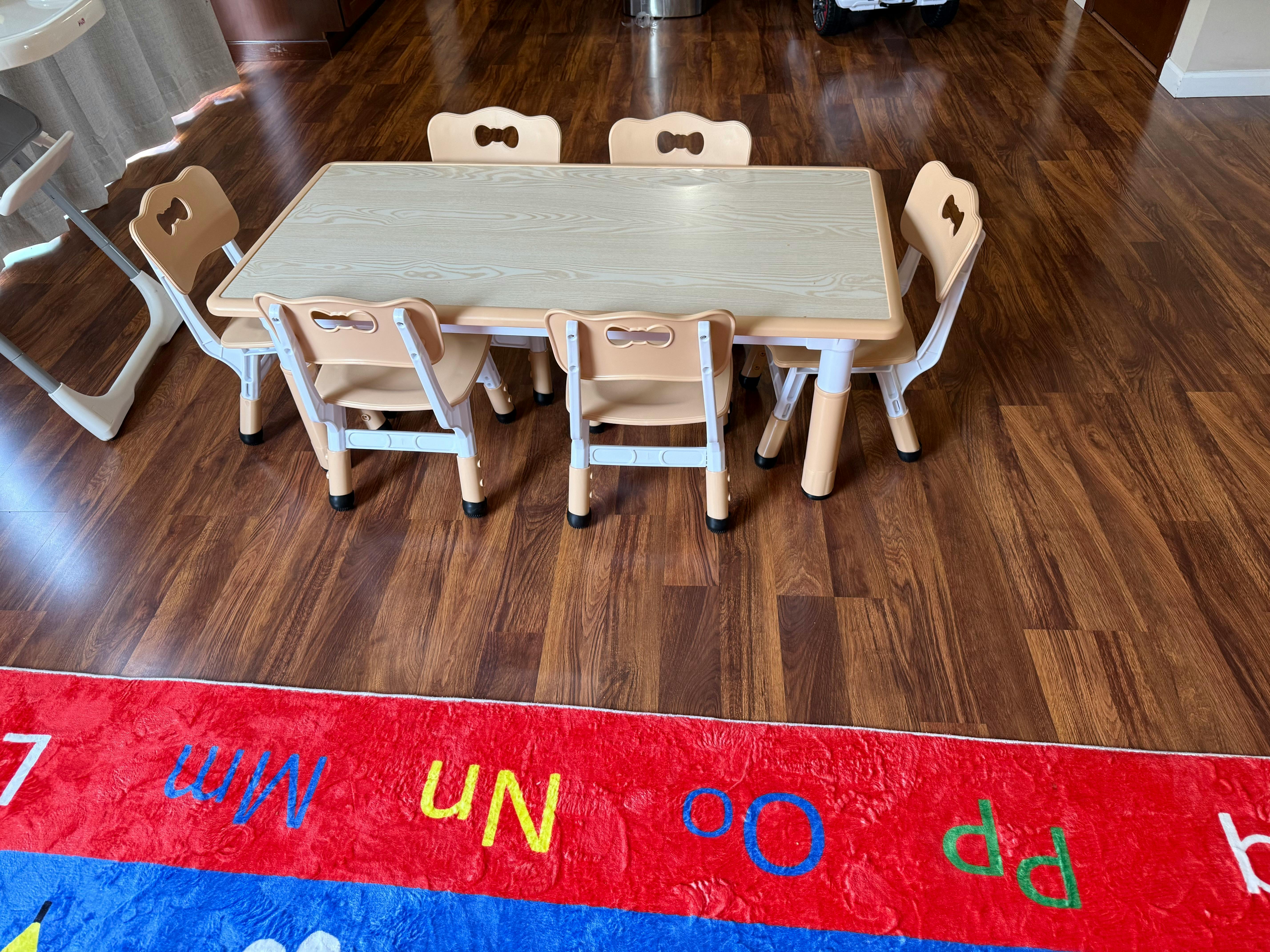 Children's table and chairs on a wooden floor with a colorful rug