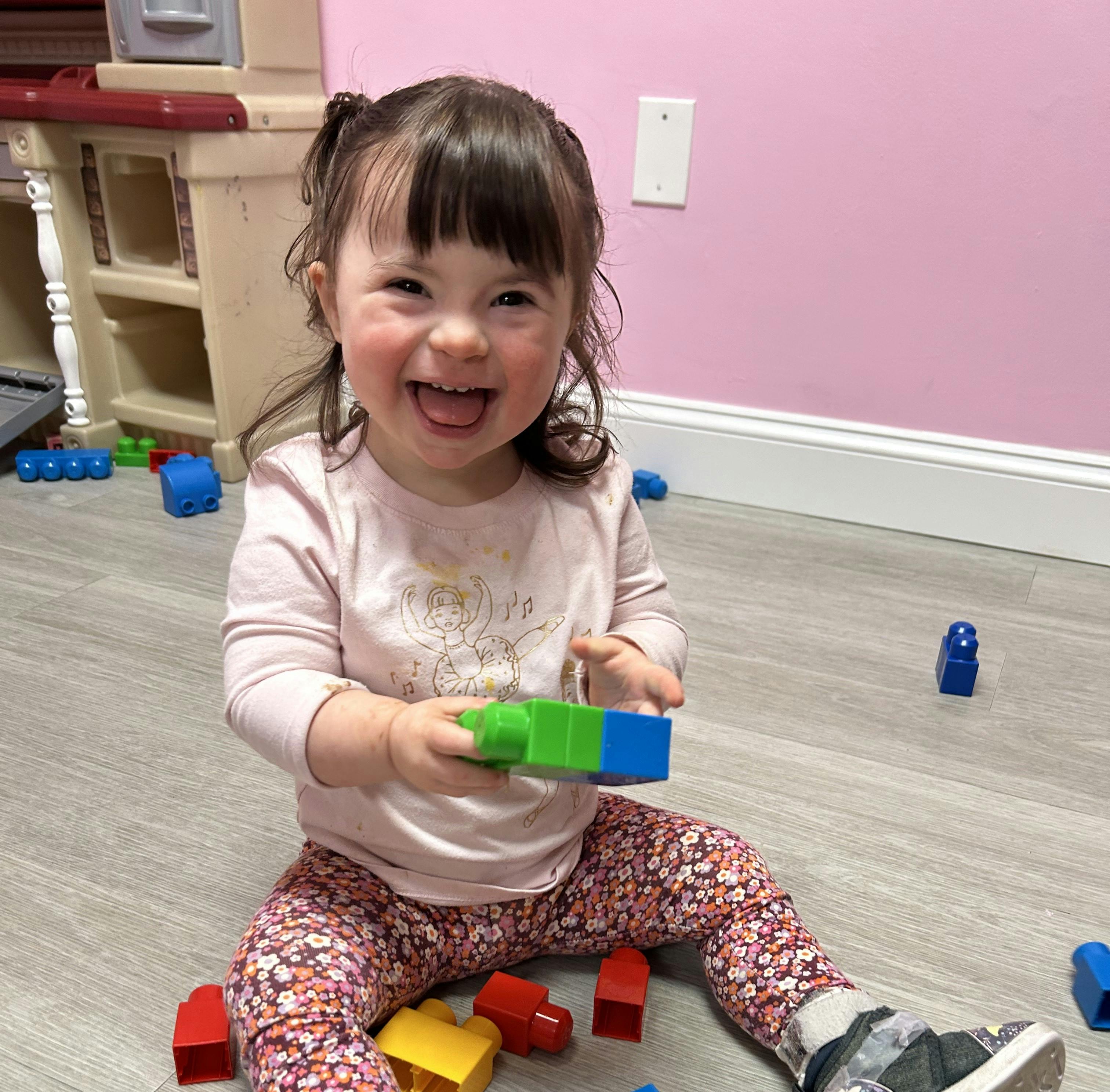 Child sitting on floor holding building blocks