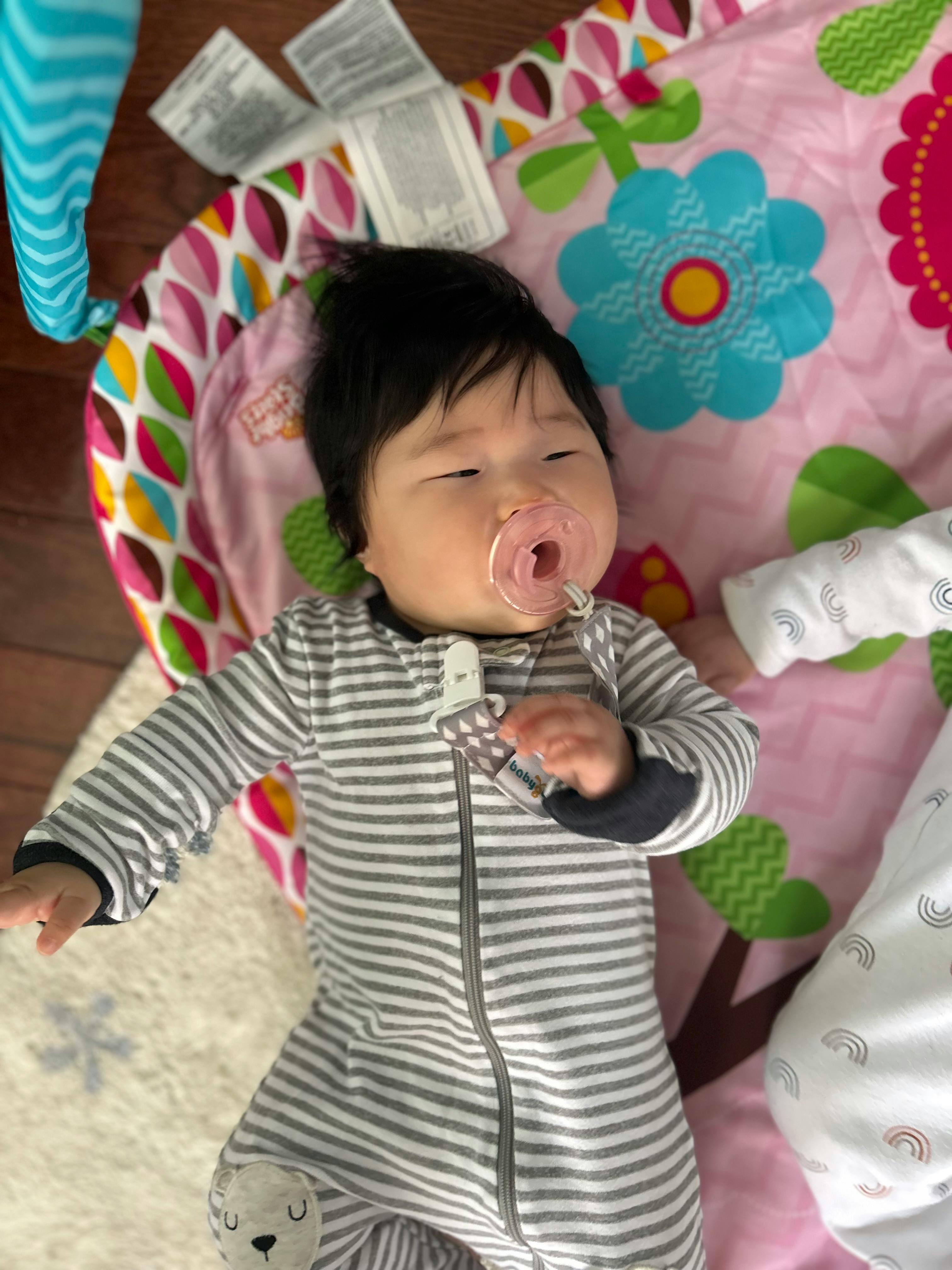 Child with a pacifier lying on a playmat
