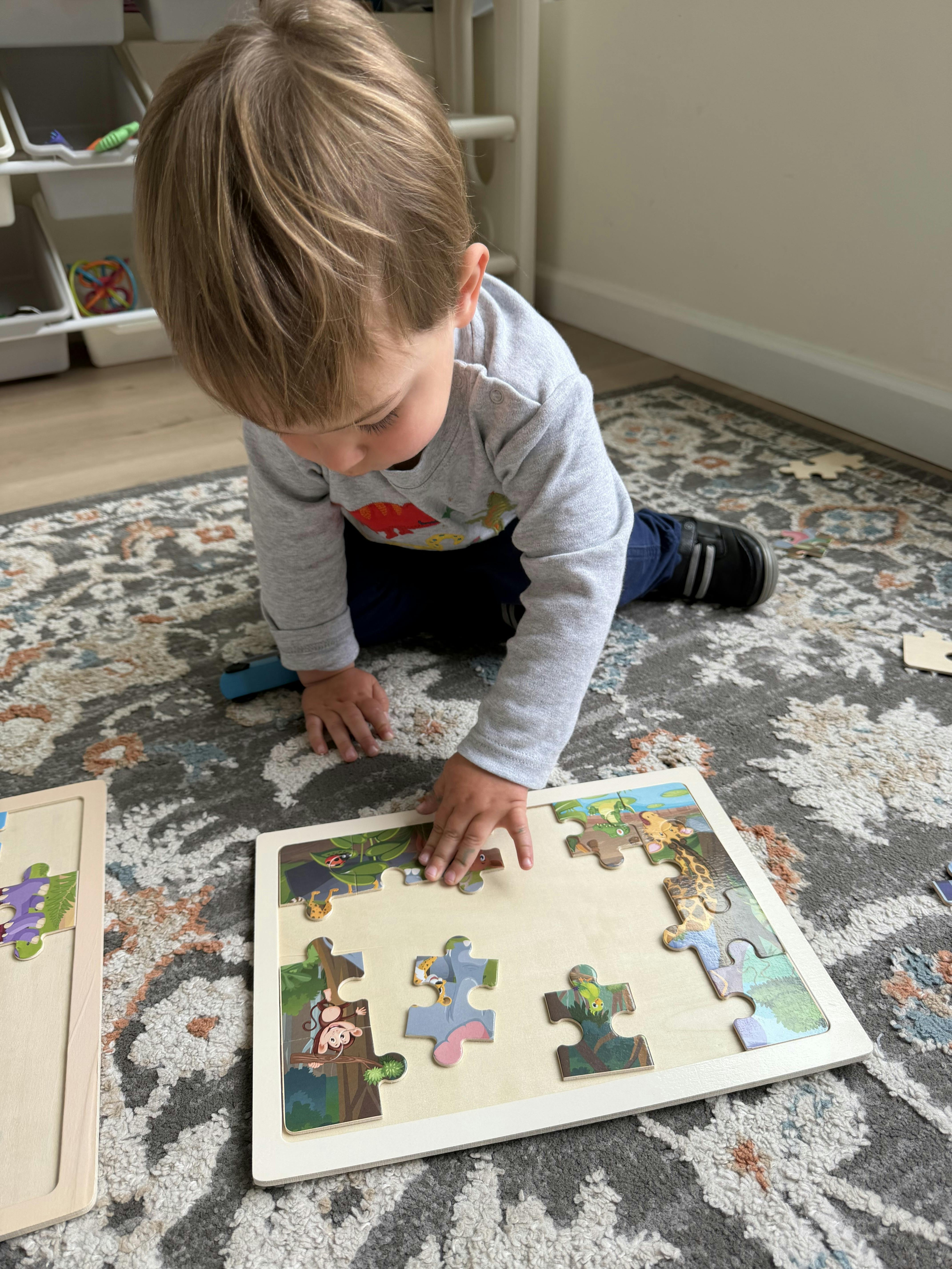 Child placing a piece into a jungle animal puzzle on the floor