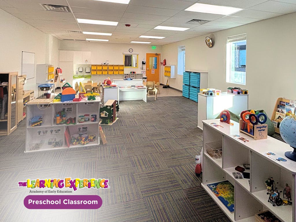 Spacious, brightly lit preschool classroom with various activity stations and toys