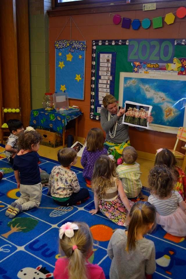 Person showing a picture to a group of children in a classroom