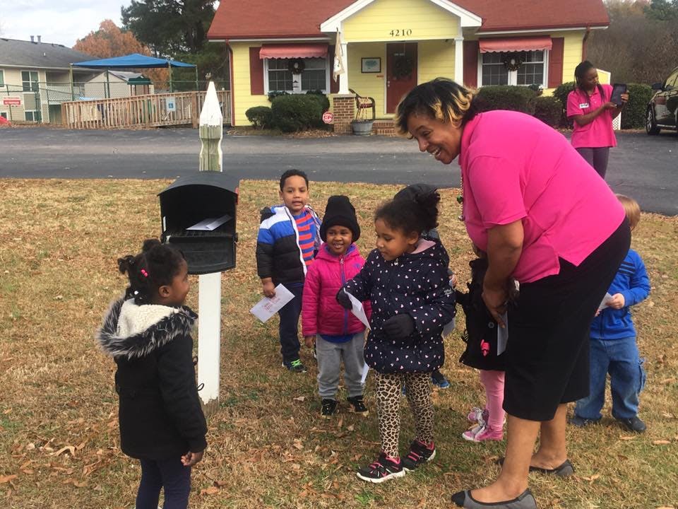 Adult and children gathered around a mailbox