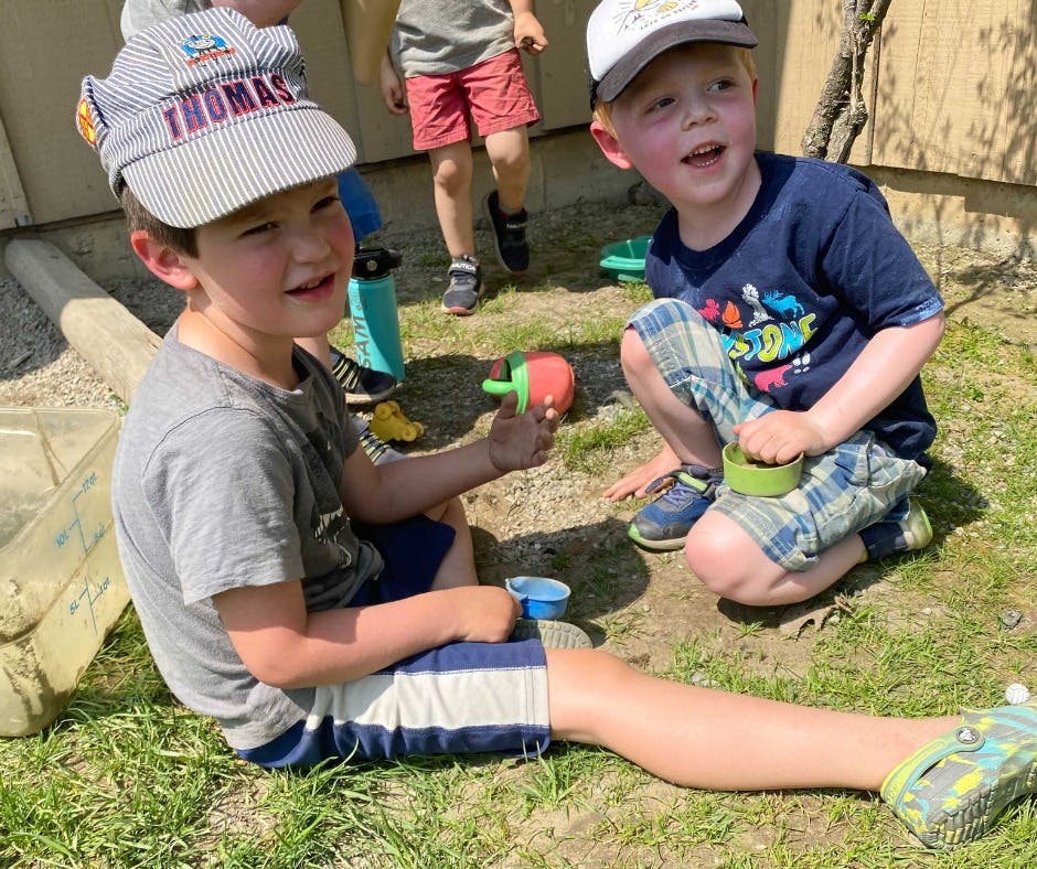 Two children playing outdoors with toys