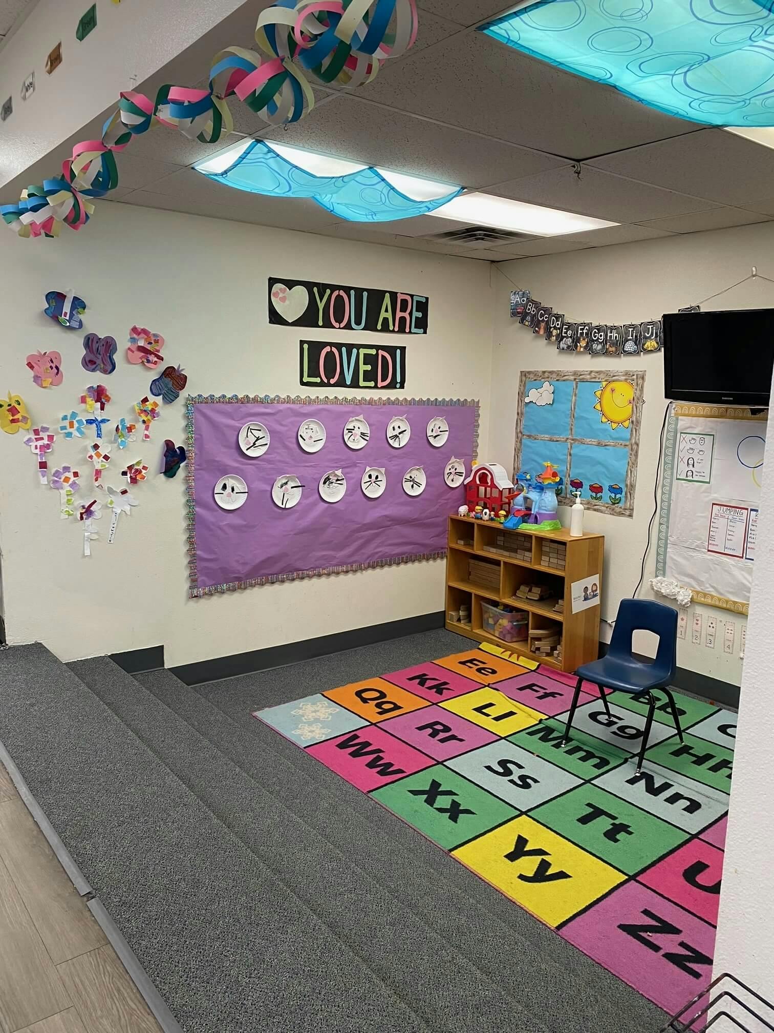 Children's classroom with alphabet rug, toys, and wall decorations