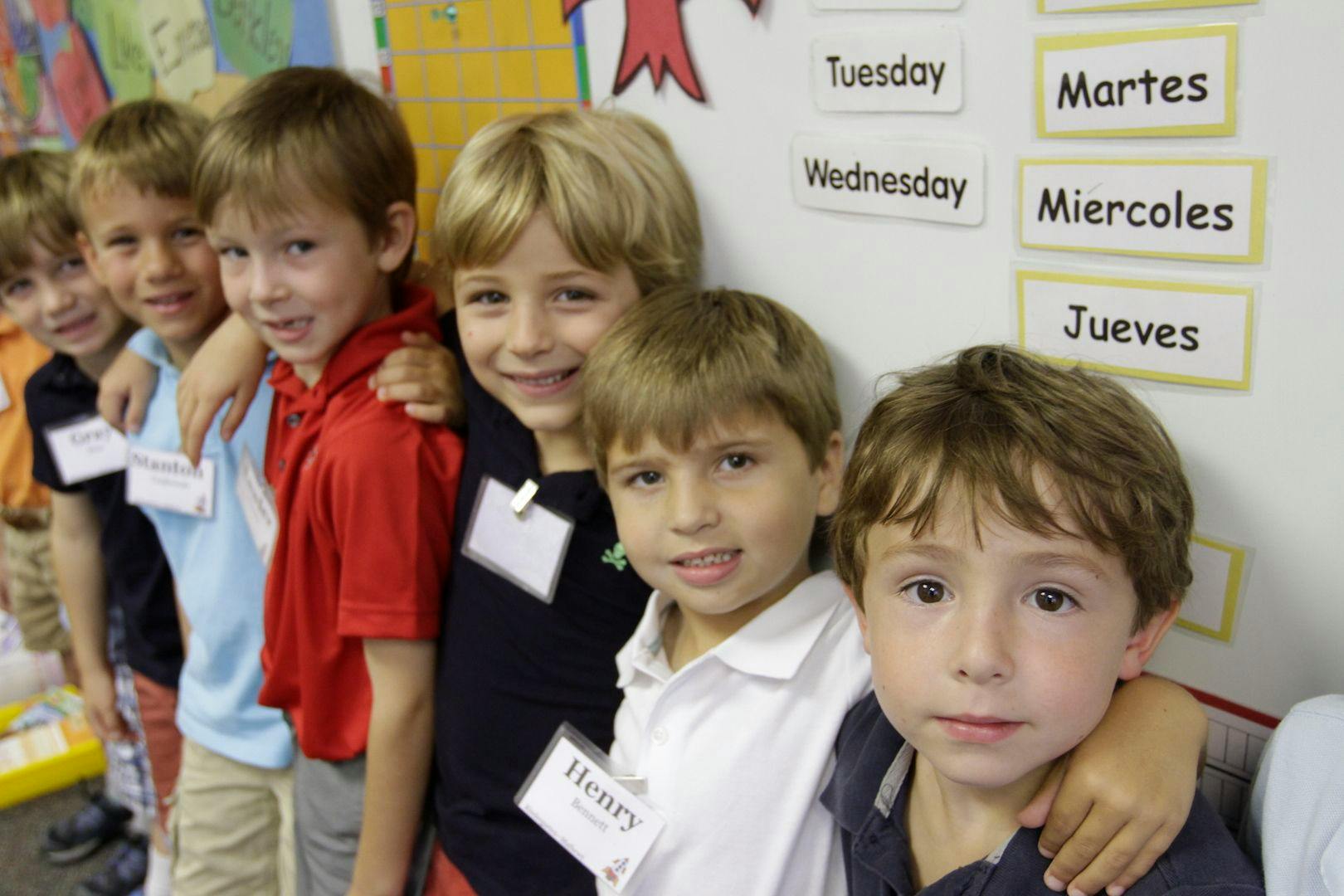 Six children standing in a line with arms around each other
