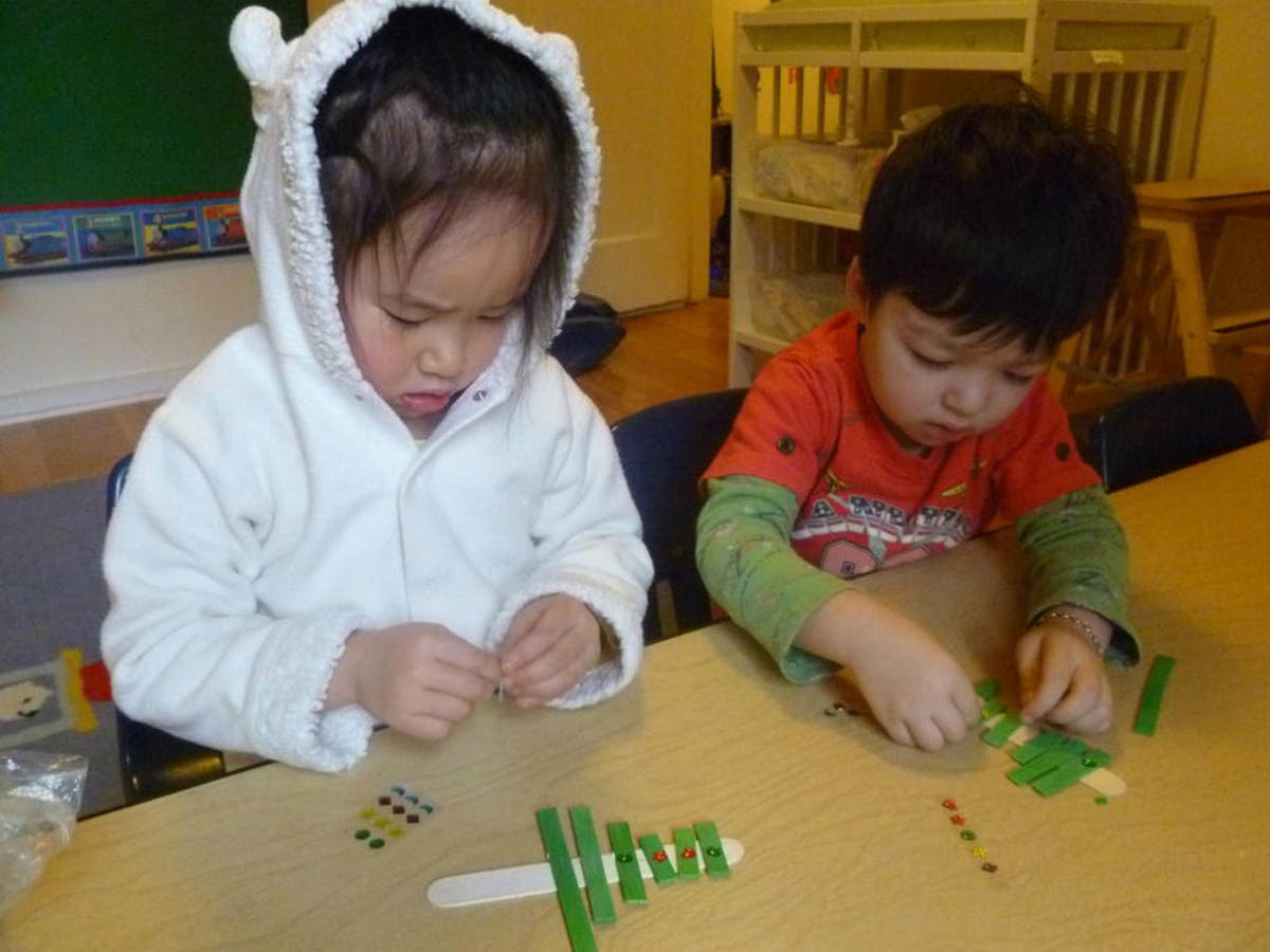 Two children at a table doing crafts with crafts