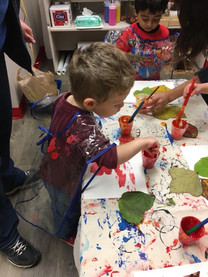 Child painting at a table with other children